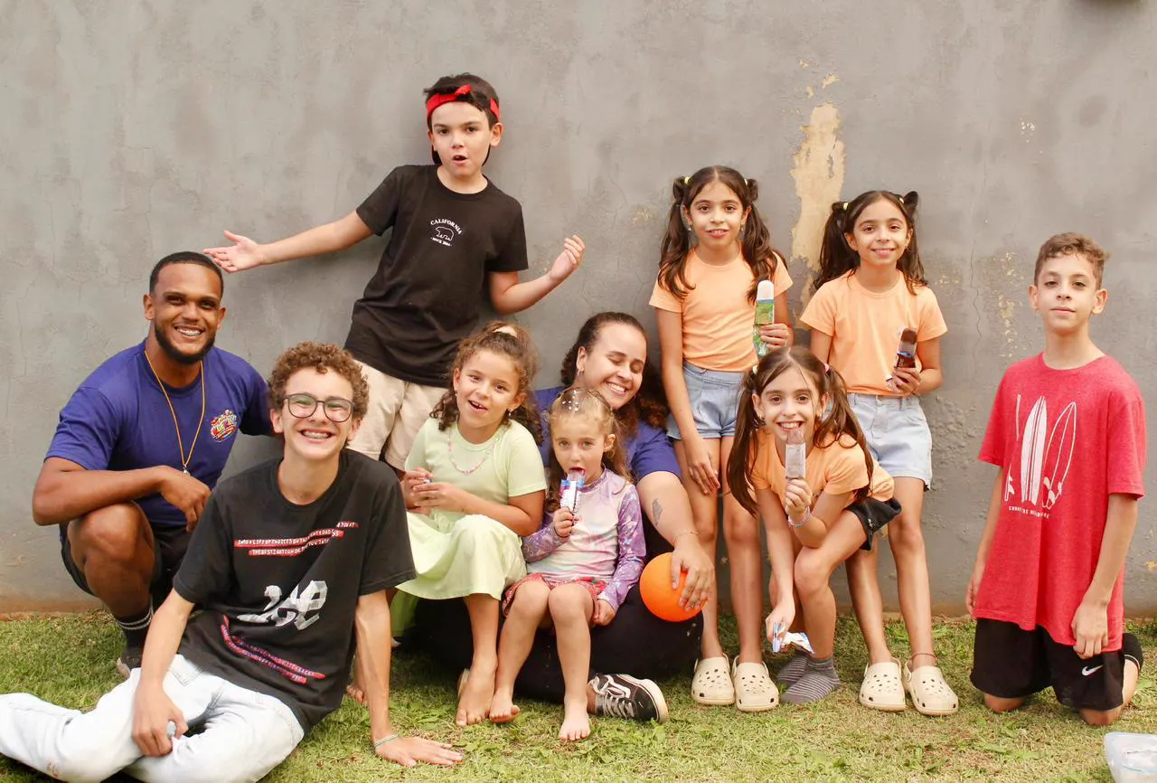 Turma de crianças e recreadores da Klif Klof sorrindo juntos na festa