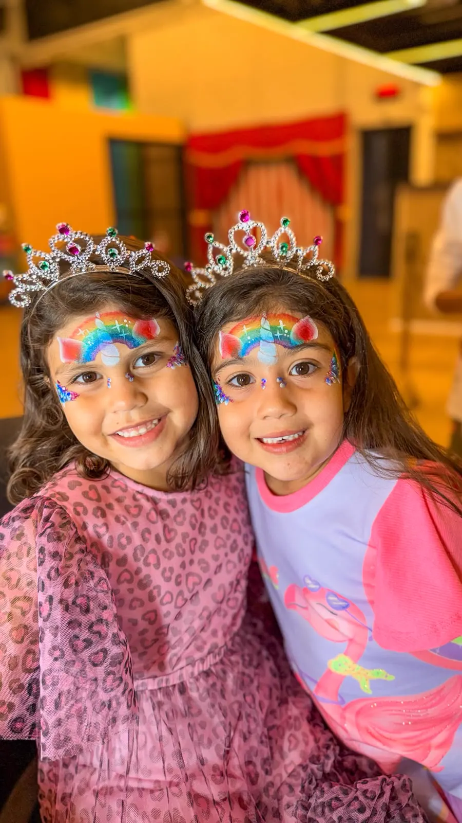 Amigas sorrindo com pintura facial de arco-íris feita pela Klif Klof