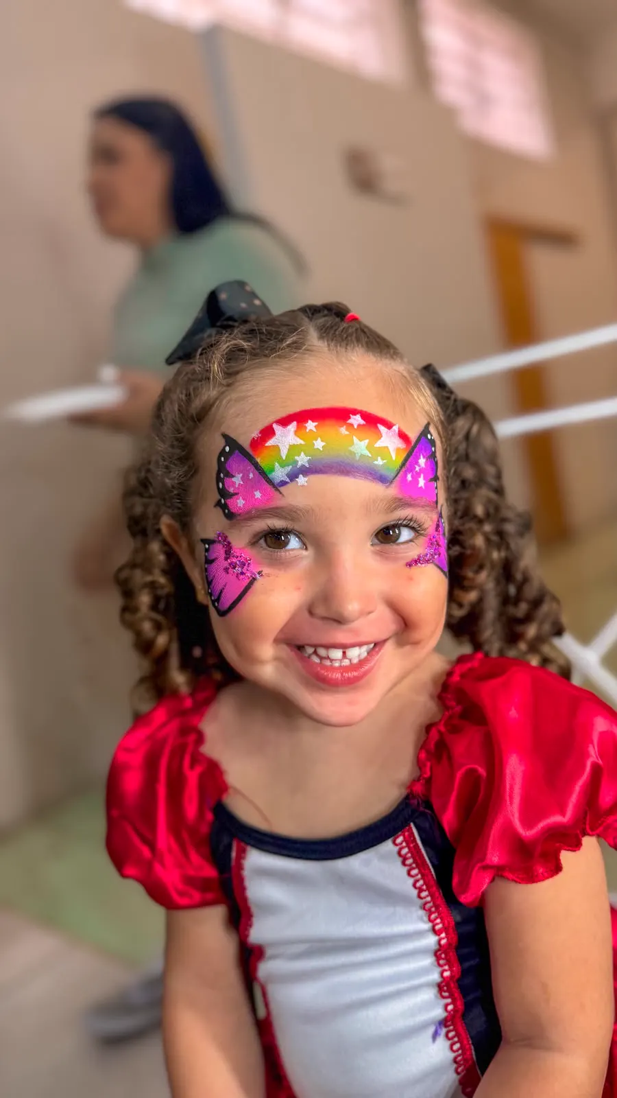 Menina com pintura facial de arco-íris
